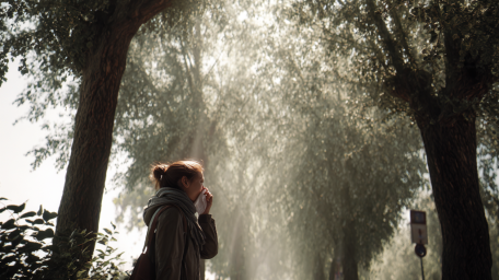 kobieta spaceruje między drzewami i kicha